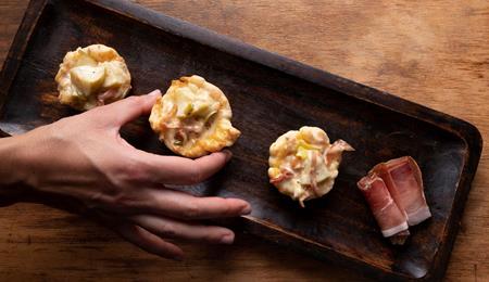 Blätterteig-Schiffchen mit Äpfeln und Speck auf einem dunklen Backblech.