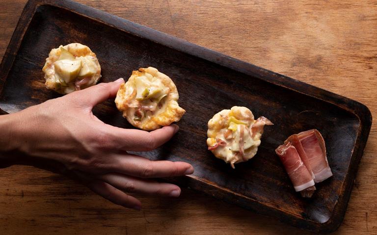 Blätterteig-Schiffchen mit Äpfeln und Speck auf einem dunklen Backblech.