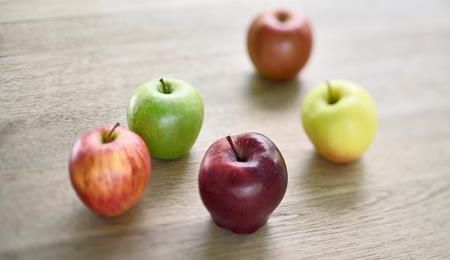 Südtiroler Äpfel in verschiedenen Farben, die auf einem Holztisch liegen.